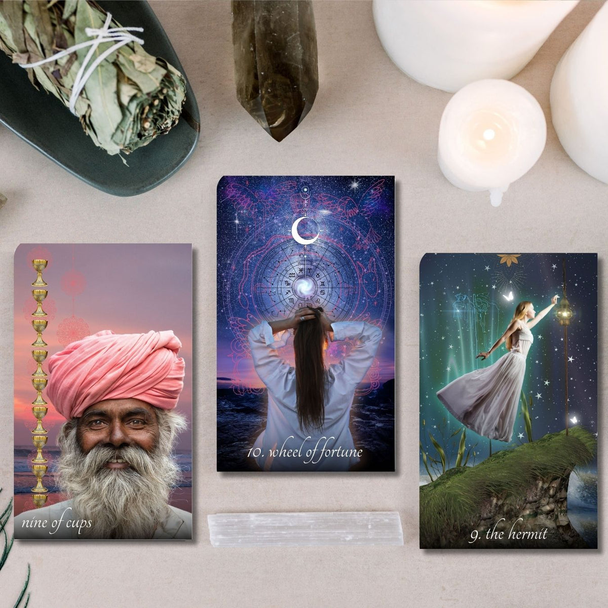 Three tarot cards displayed on a surface with candles and crystals.