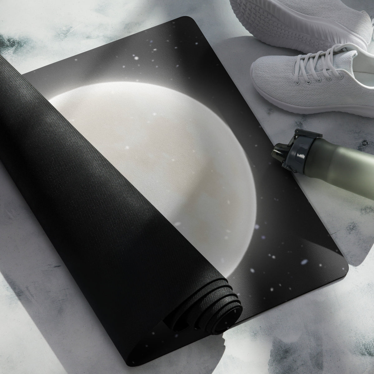 A yoga mat with a design of the moon and stars on it, rolled out next to a pair of white sneakers and a cylindrical object (presumably a pump).