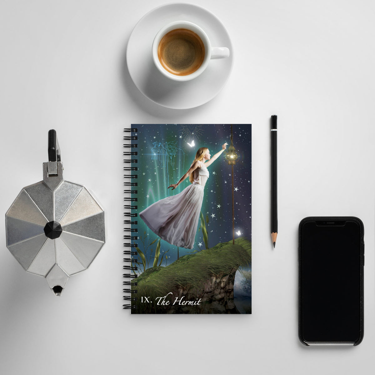 The Hermit Spiral Bound Notebook lies flat on a table with a morning espresso and phone