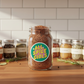 Jar of 'All Spice Girls' spice blend on a wooden surface with other spice jars in the background.